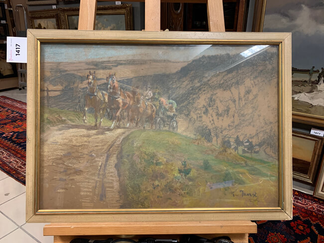 Auf einer Staffelei steht ein gerahmtes Gemälde. Es zeigt eine von braunen Pferden gezogene Kutsche auf einer Landstraße in den Bergen. Das Gemälde ist unten rechts signiert und oben links am Rahmen befindet sich ein Zettel mit einer Beschriftung und der Nummer 1417.