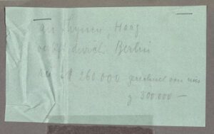 Ein kleiner Zettel wurde auf einen grauen Untergrund getackert. Der Zettel ist handschriftlich beschrieben, unteranderem ist darauf zu lesen: "an Thyssen, Haag verkauft durch Berlin".