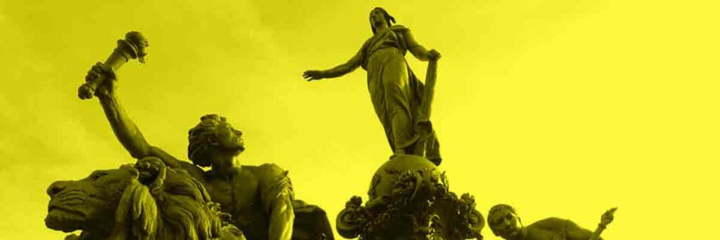 Eine großes Monument aus dunkelgrünem Metall. Die Statue einer Frau mit phrygischer Mütze und Rutenbündel steht auf einem reich dekorierten Wagen der von zwei Löwen gezogen wird. Sie wird von einer weiteren Frau und einem Mann, der eine Fackel in die Höhe reckt, begleitet. Alles ist gelb eingefärbt.