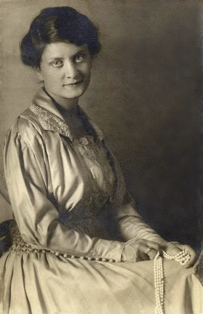 Porträt einer sitzenden Frau in historischer Kleidung mit Perlenkette in den Händen