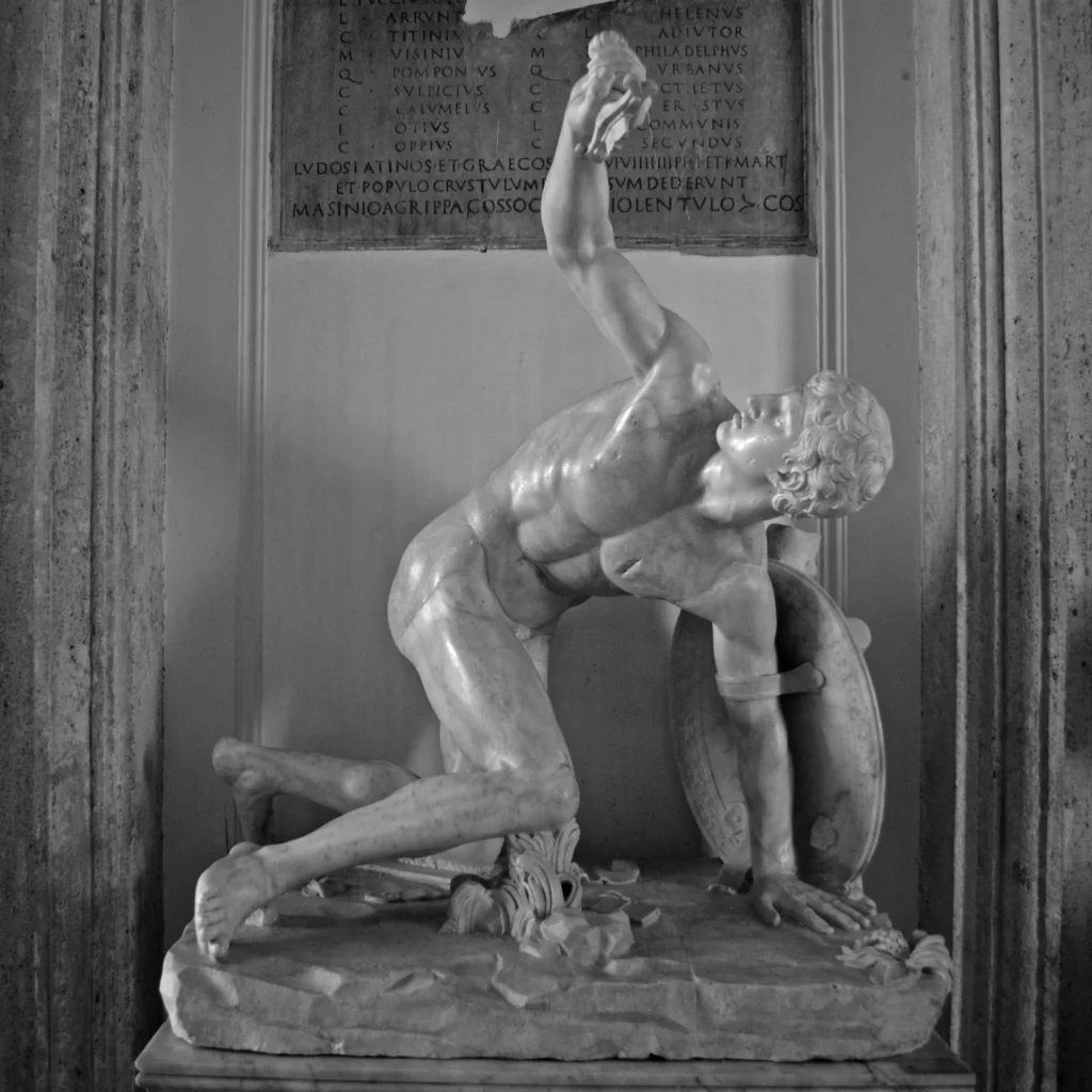 Marmorskulptur eines knienden, muskulösen Mannes mit erhobenem Arm und Schild hinter dem Rücken in einem Nischenrahmen
